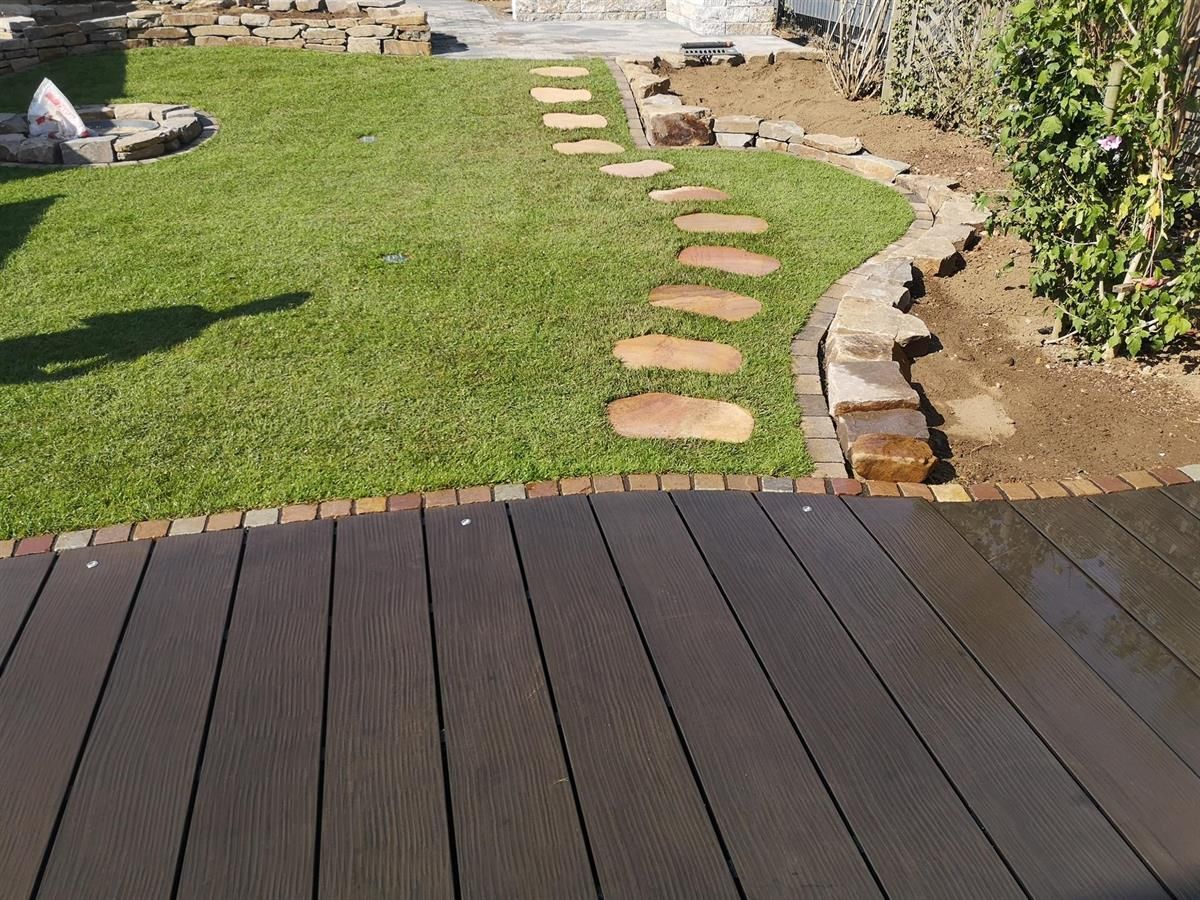 Ein Holzdeck ist von einem üppigen grünen Rasen umgeben