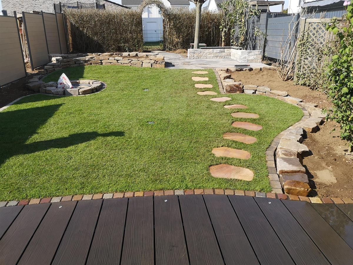 Ein üppiger grüner Rasen mit einem Holzdeck im Vordergrund