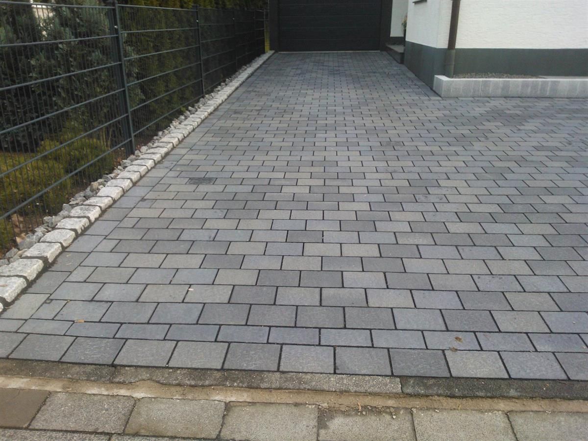 Eine gemauerte Auffahrt mit einem Zaun im Hintergrund