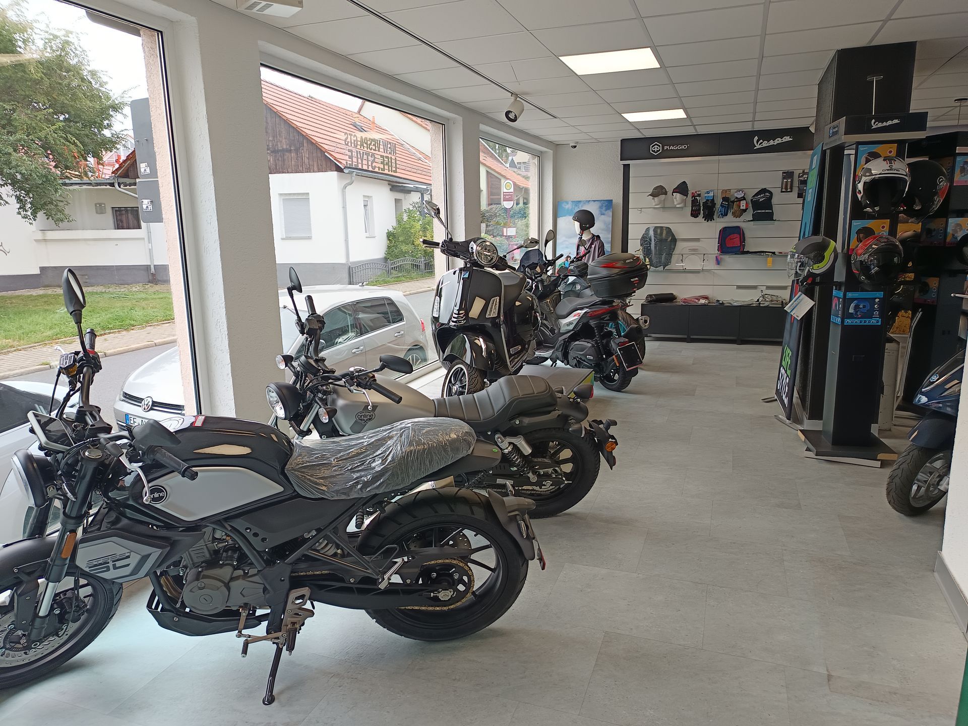 Innenansicht eines Motorrad-Showrooms: Mehrere geparkte Motorräder, große Fenster und helle Beleuchtung.