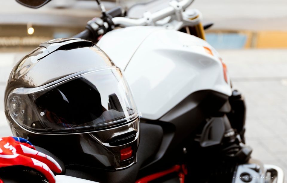 Schwarzer Motorradhelm liegt auf einem weißen Motorrad, Nahaufnahme.