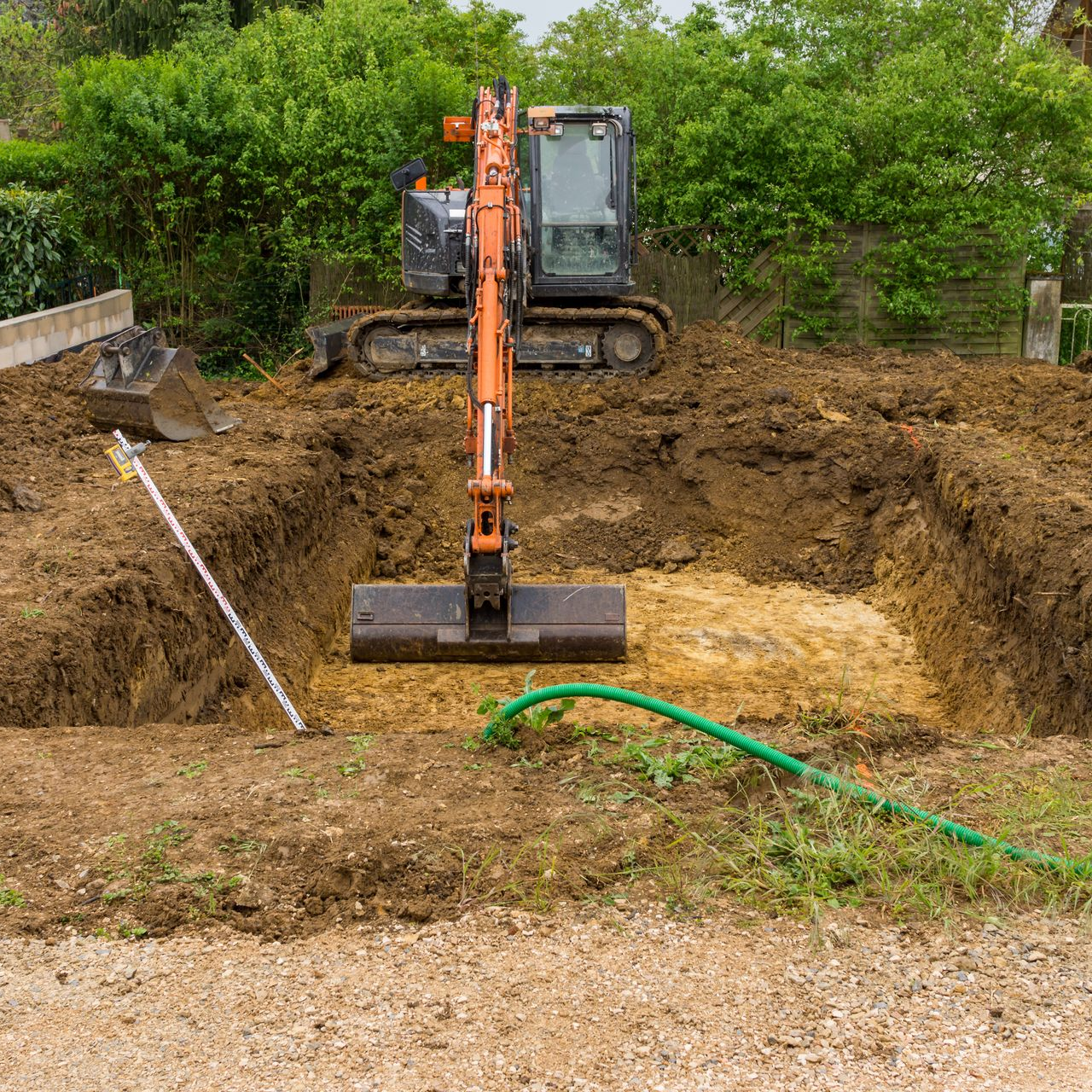 Un engin de chantier creuse un trou pour une piscine.