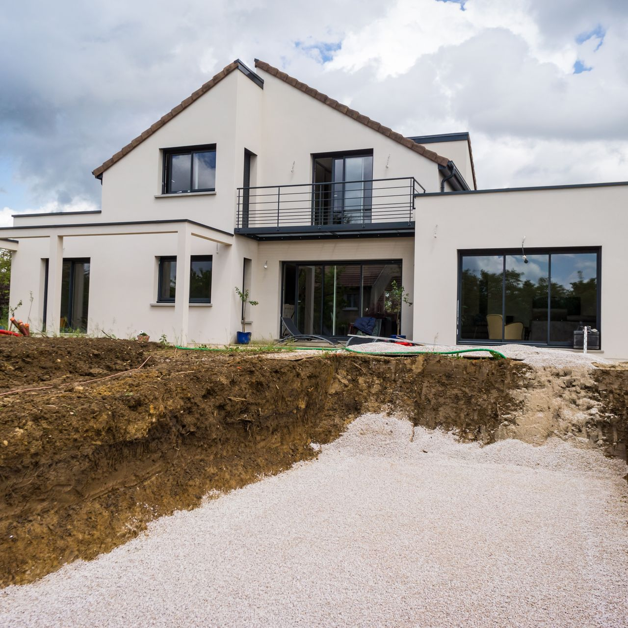 Terrassement pour une future piscine dans le jardin d'une maison contemporaine.