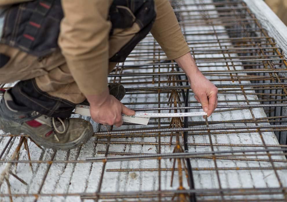 Ein Mann misst ein Stück Metall mit einem Lineal.