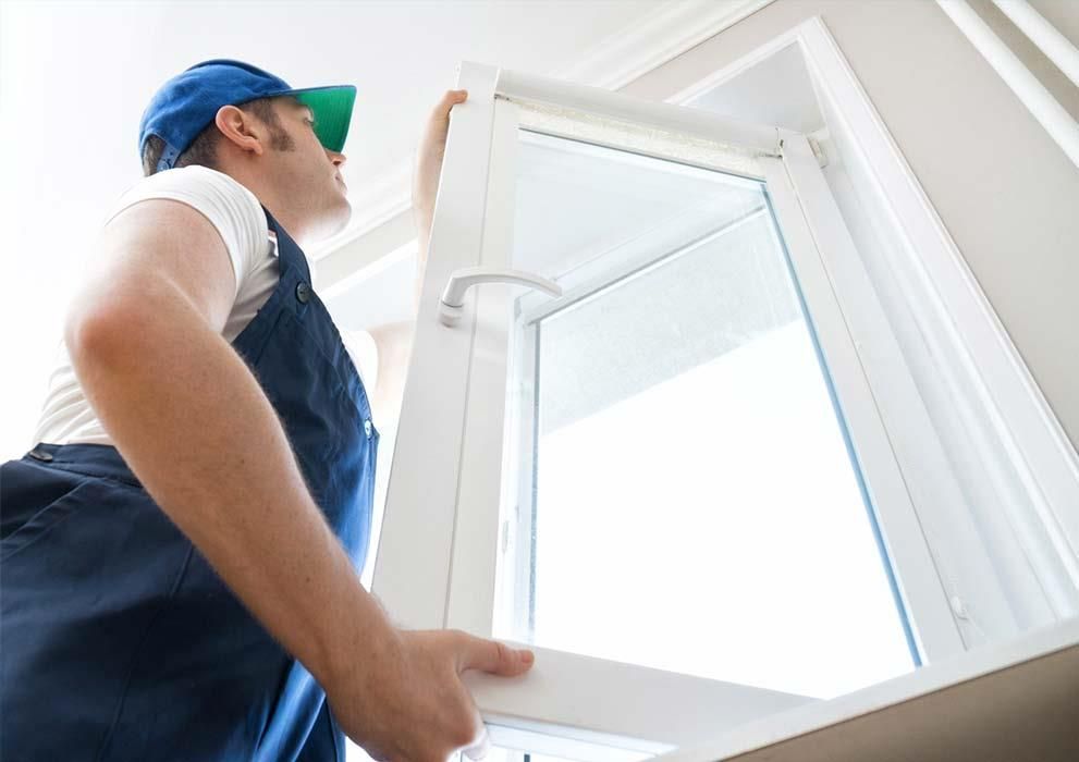 Ein Mann baut ein Fenster in einem Haus ein.