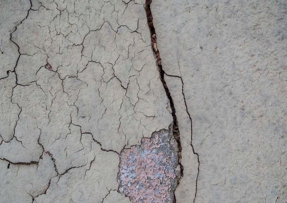 Eine Nahaufnahme einer rissigen Betonoberfläche mit einem Stein in der Mitte.