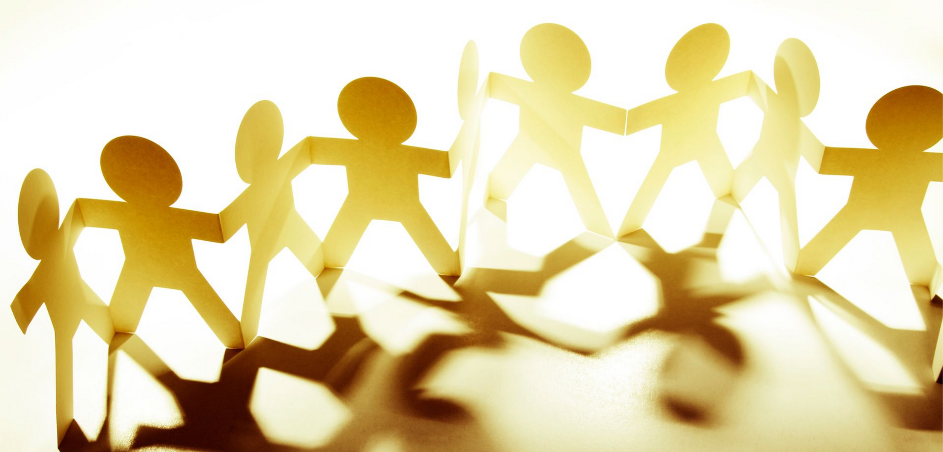 Une guirlande de silhouettes en papier doré découpées et reliées entre elles en un cercle, sur un fond lumineux