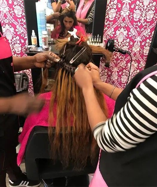 Varias extensiones de cabello ondulado, castaño y rojizo, colgadas en fila.