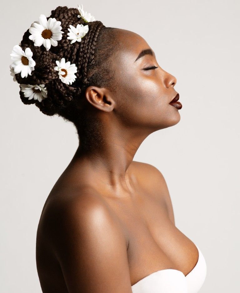 Retrato de perfil de una mujer con adornos florales en el cabello, con los ojos cerrados.