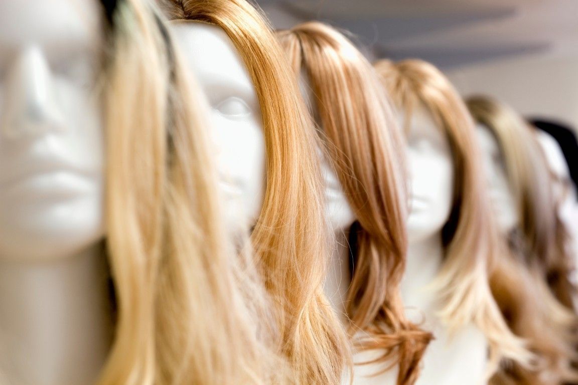 Fila de cabezas de maniquí rubias con cabello largo en el escaparate de una tienda.