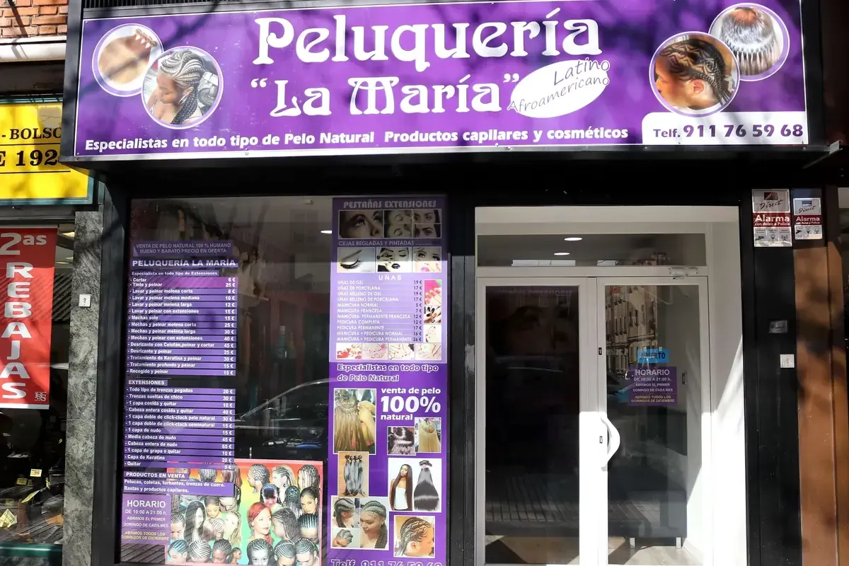 Peinado con trenzas siendo arreglado frente al espejo de una peluquería con paredes estampadas en rosa.
