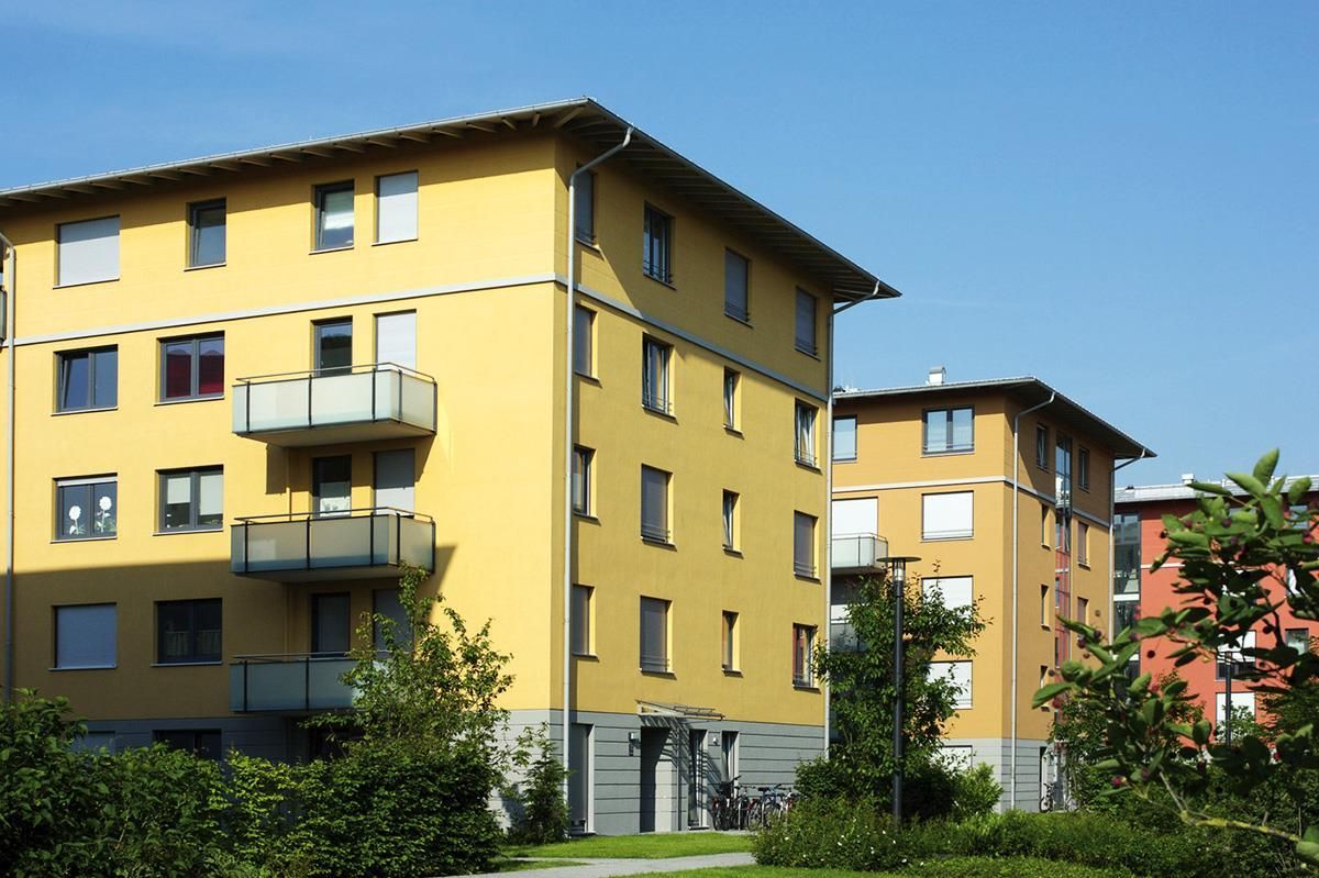 Ein gelbes Gebäude mit Balkonen und einem blauen Himmel im Hintergrund