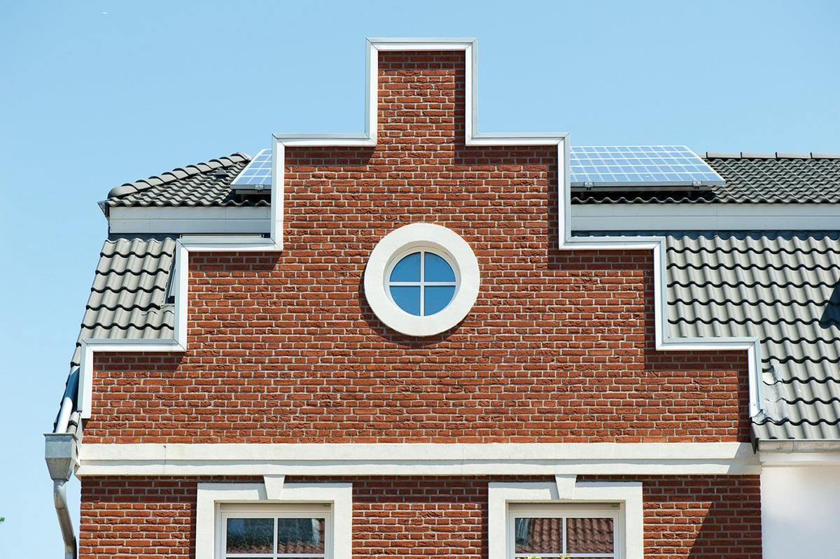 Ein Backsteingebäude mit einem Fenster und Sonnenkollektoren auf dem Dach