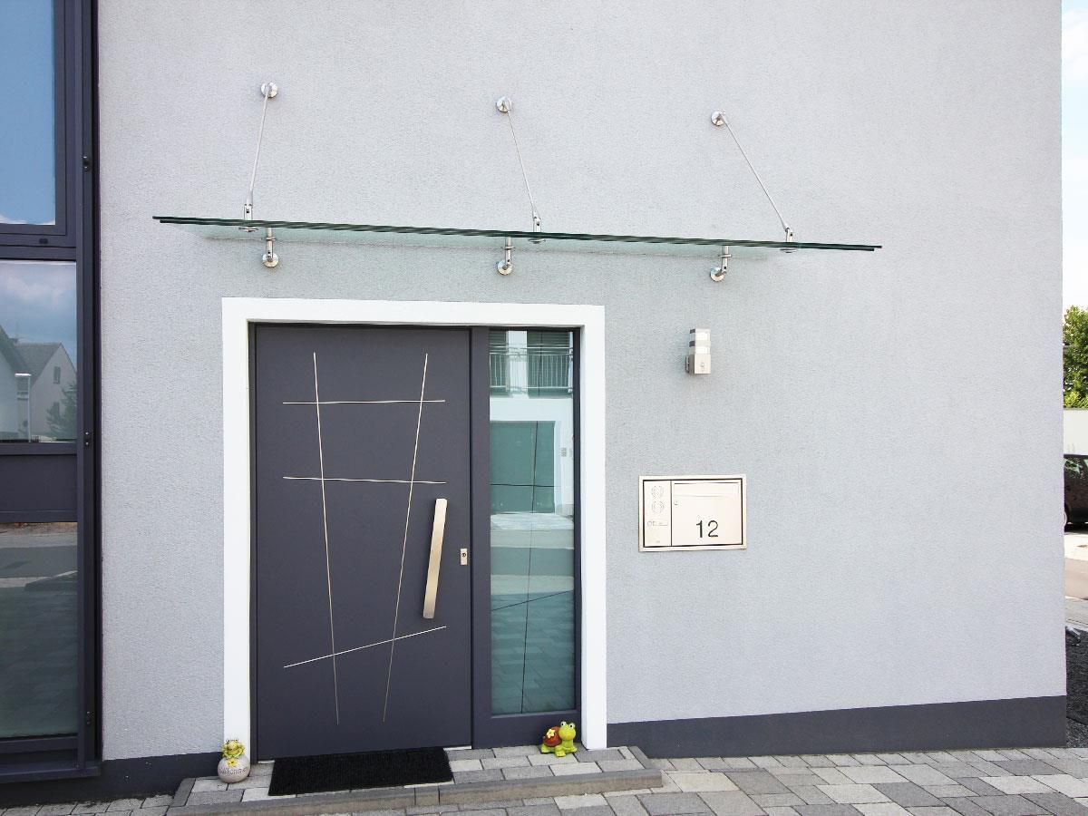 Ein graues Gebäude mit einer schwarzen Tür und einem Glasdach