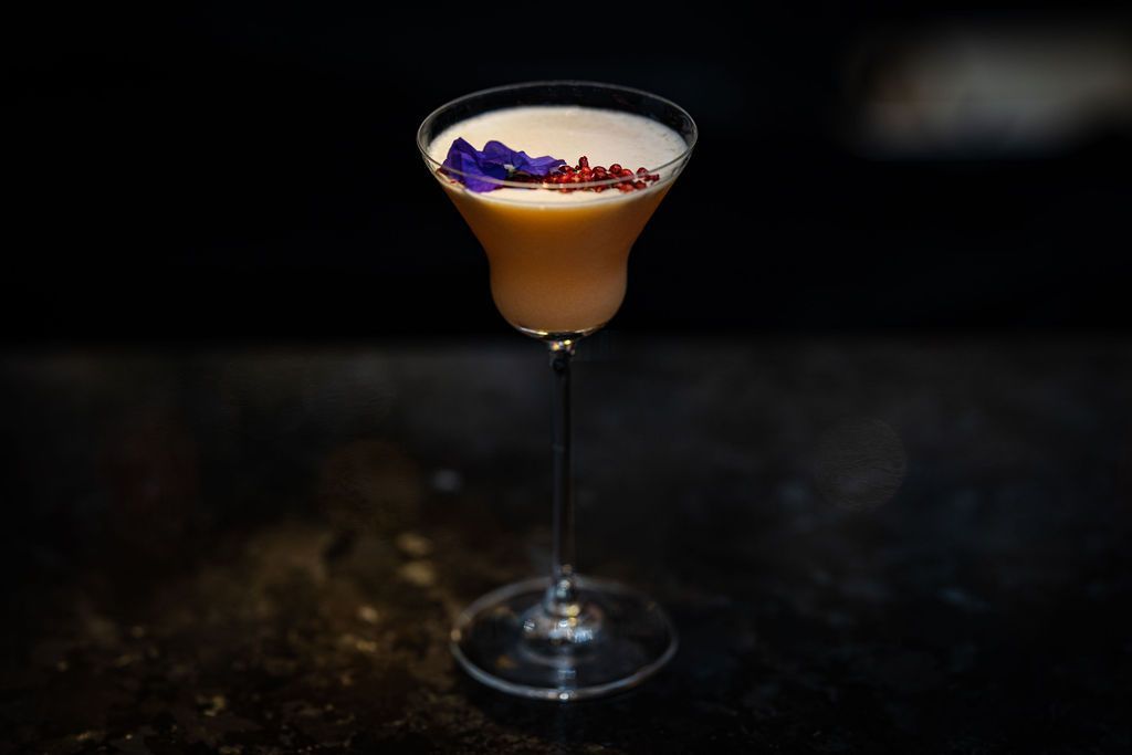 A close up of a cocktail in a martini glass on a table.