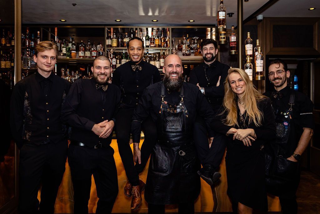 A group of people are posing for a picture in front of a bar.