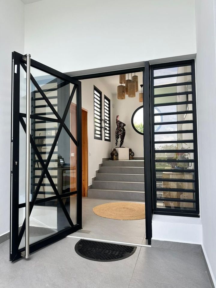 Une porte d'entrée vitrée avec des jalousies de sécurité de chaque côté.
