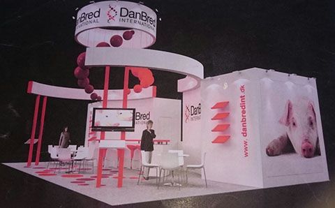 Stand de feria comercial de DanBred International, blanco y rojo con un gráfico de cerdo y gente presente.