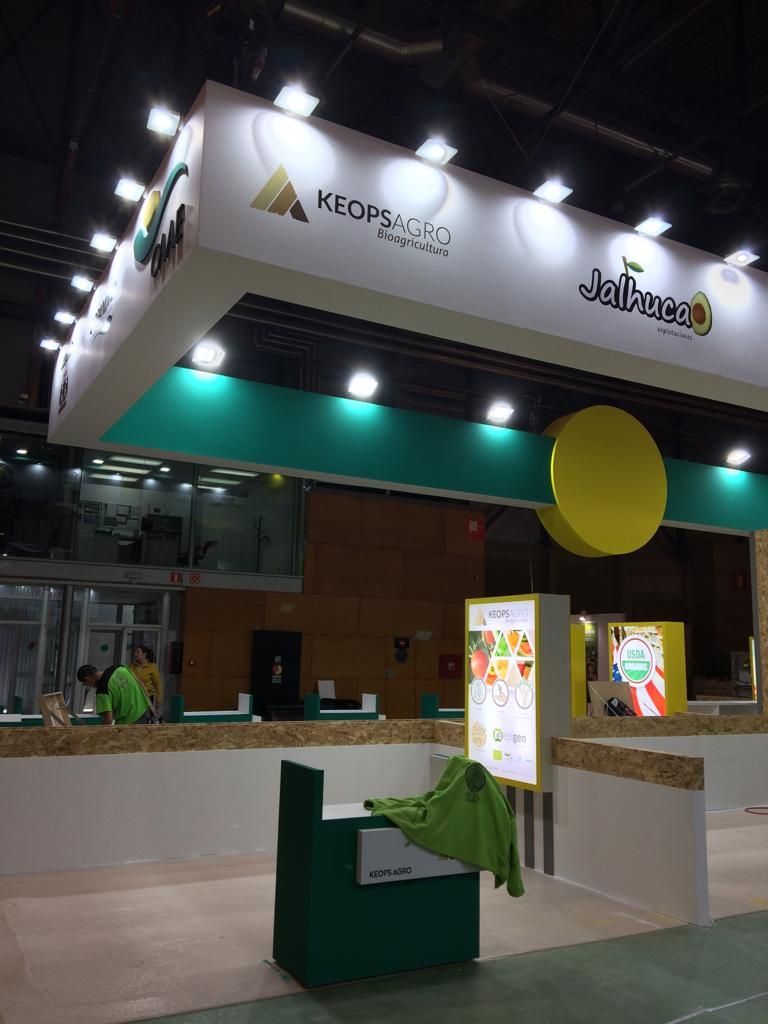 Stand de exposición con diseño en blanco, verde y amarillo; el logotipo 