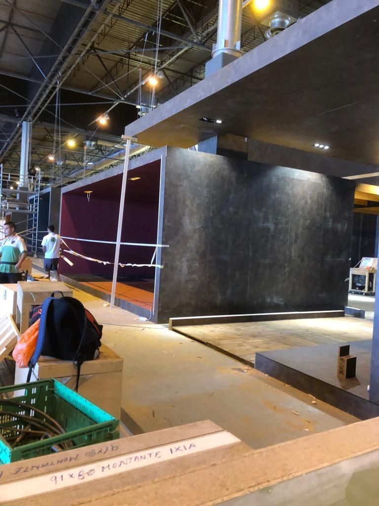 Vista interior de un edificio en construcción, que presenta una estructura en forma de caja de color gris oscuro con un interior rojo.