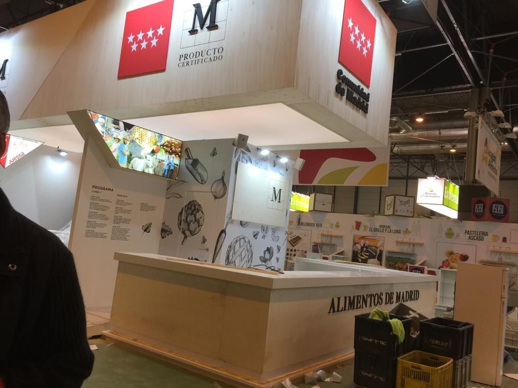 Stand de alimentación del Gobierno Regional de Madrid en una feria comercial, con el logotipo en un lugar destacado.