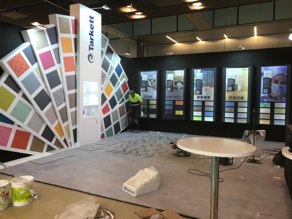 Stand con muestras de colores, persona trabajando en pisos y exhibiciones de productos; marca Parker.