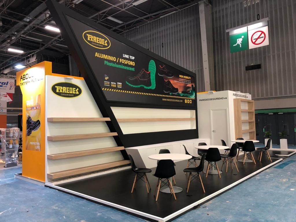 Un stand de feria comercial con detalles en blanco y negro, con estantes, mesas e información sobre productos.