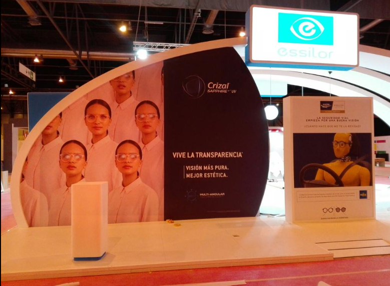 Stand con personas en batas de laboratorio y gafas. Texto 