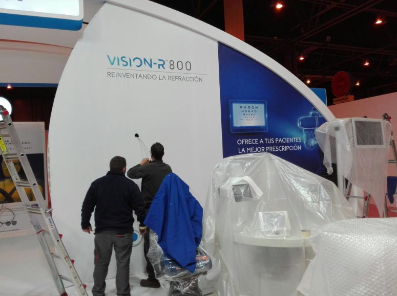 Dos hombres instalando un stand en una feria comercial con la señalización 