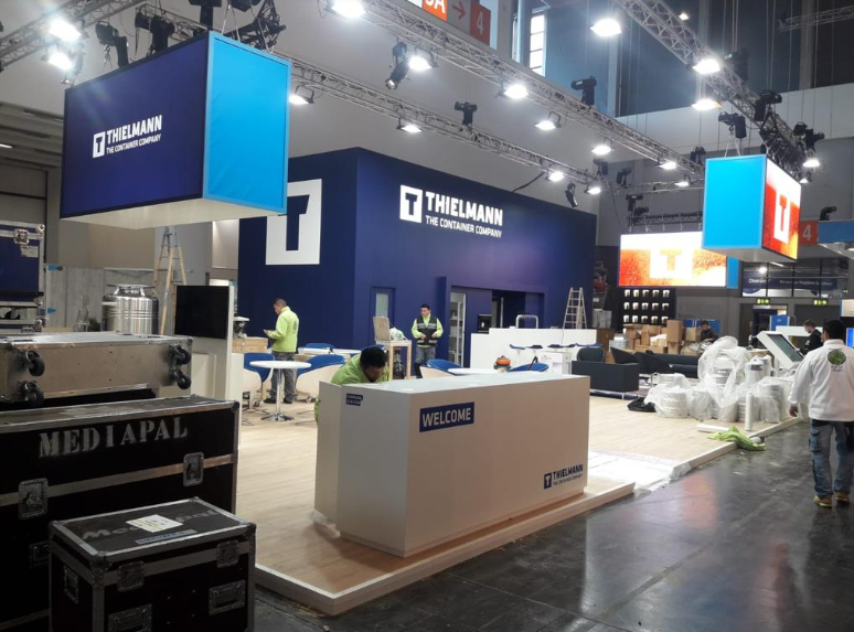 Stand de feria con temática azul y blanca. Trabajadores montan la exhibición de Thielmann.