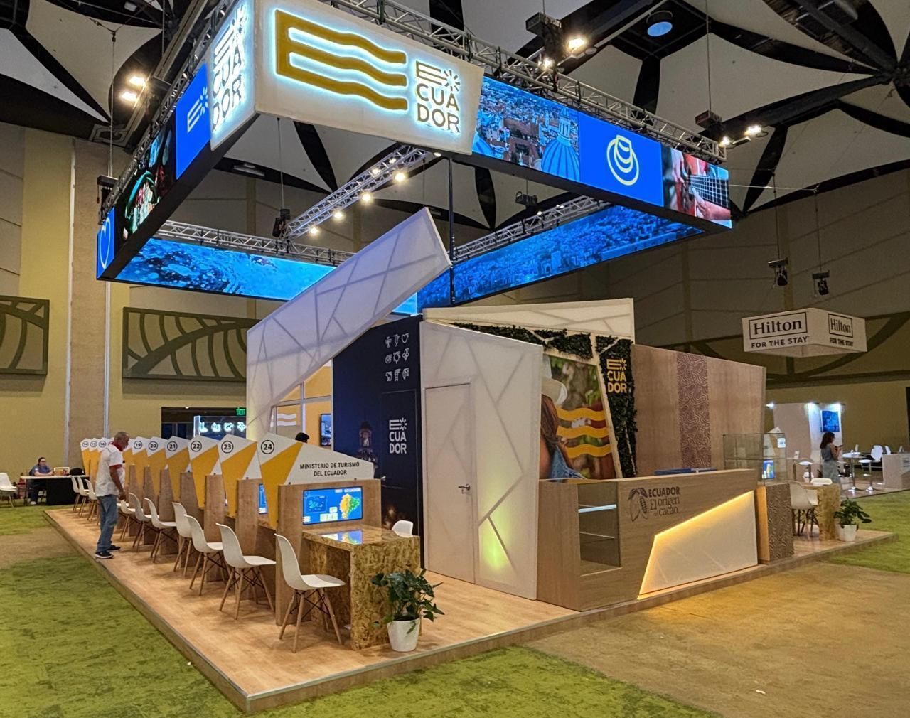 Stand de feria con un gran cartel. Muestras y asientos.