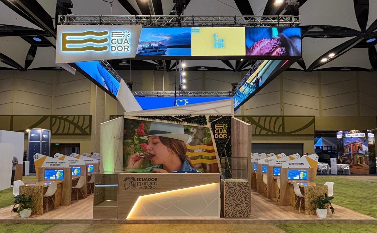 Stand de feria con displays y pantallas, en el que aparece una persona comiendo fruta y el logo de