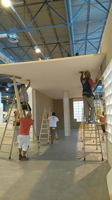 Los trabajadores de la construcción instalan un techo suspendido en un gran espacio interior.