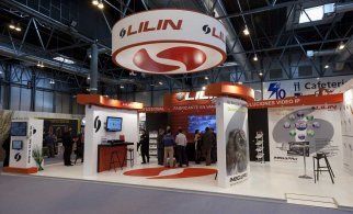 Stand de LILIN en una feria comercial; gente de pie, marcas blancas, rojas y plateadas, exhibidores y monitores.