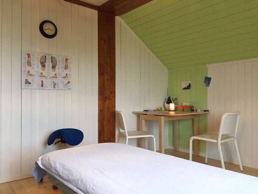 Kleines Schlafzimmer mit Bett, weissen Stühlen, Tisch und grüner Dachschräge.