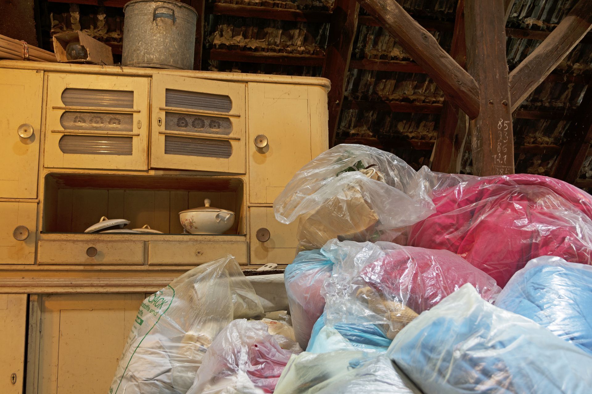 Une vieille armoire jaune à côté de piles de sacs en plastique dans un espace de stockage rustique.