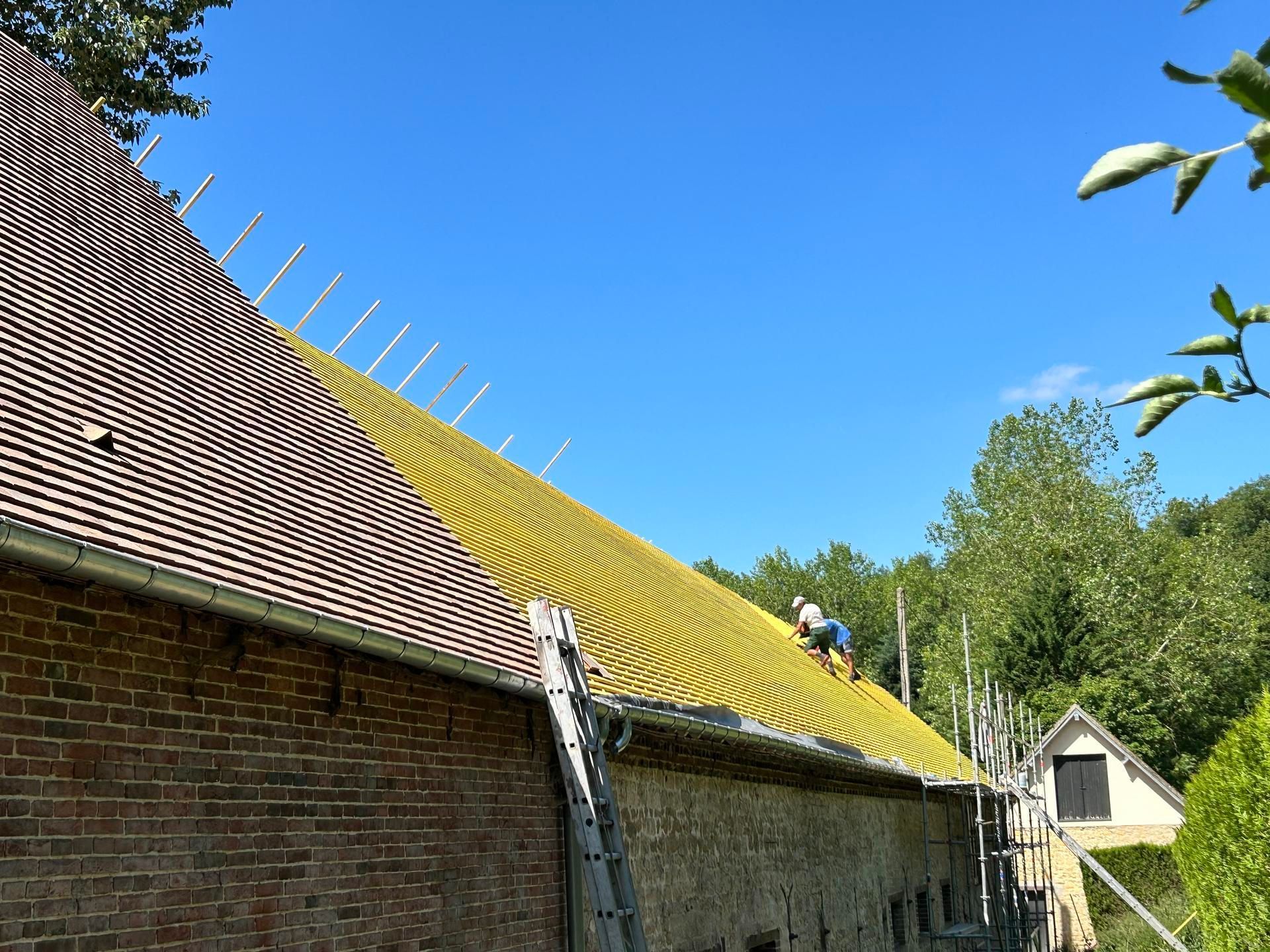Deux couvreurs sur une toiture en construction.