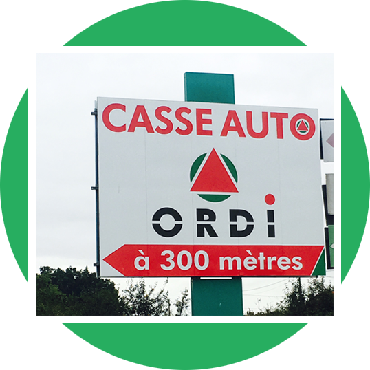 Panneau Casse Auto ORDI (pièces automobiles) en rouge et blanc, pointant vers une direction à 300 mètres, sur fond vert.