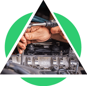 Mains d'un mécanicien travaillant sur un moteur avec une clé, à l'intérieur d'un triangle vert.