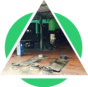 L'intérieur d'un atelier de réparation automobile, encadré de formes géométriques vertes. Plusieurs roues sont posées au sol.