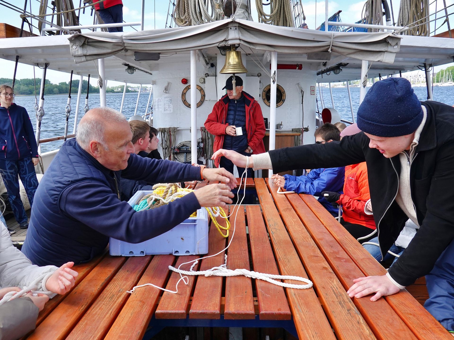 Eine Gruppe von Leuten lernt die Knotenkunde auf einem Schiff