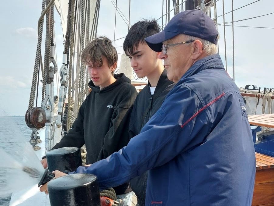 Eine Person erklärt die Funktionsweise der Feuerspritzen an Bord eines Segelschiffs