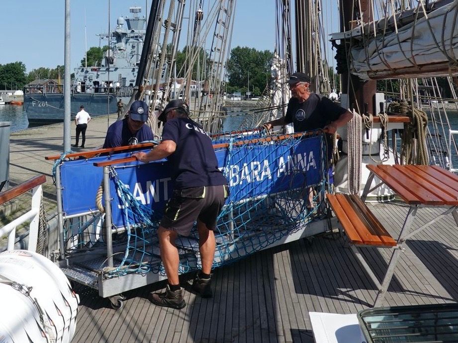 Die Crew eines Segelschiffes holt die Gangway ein