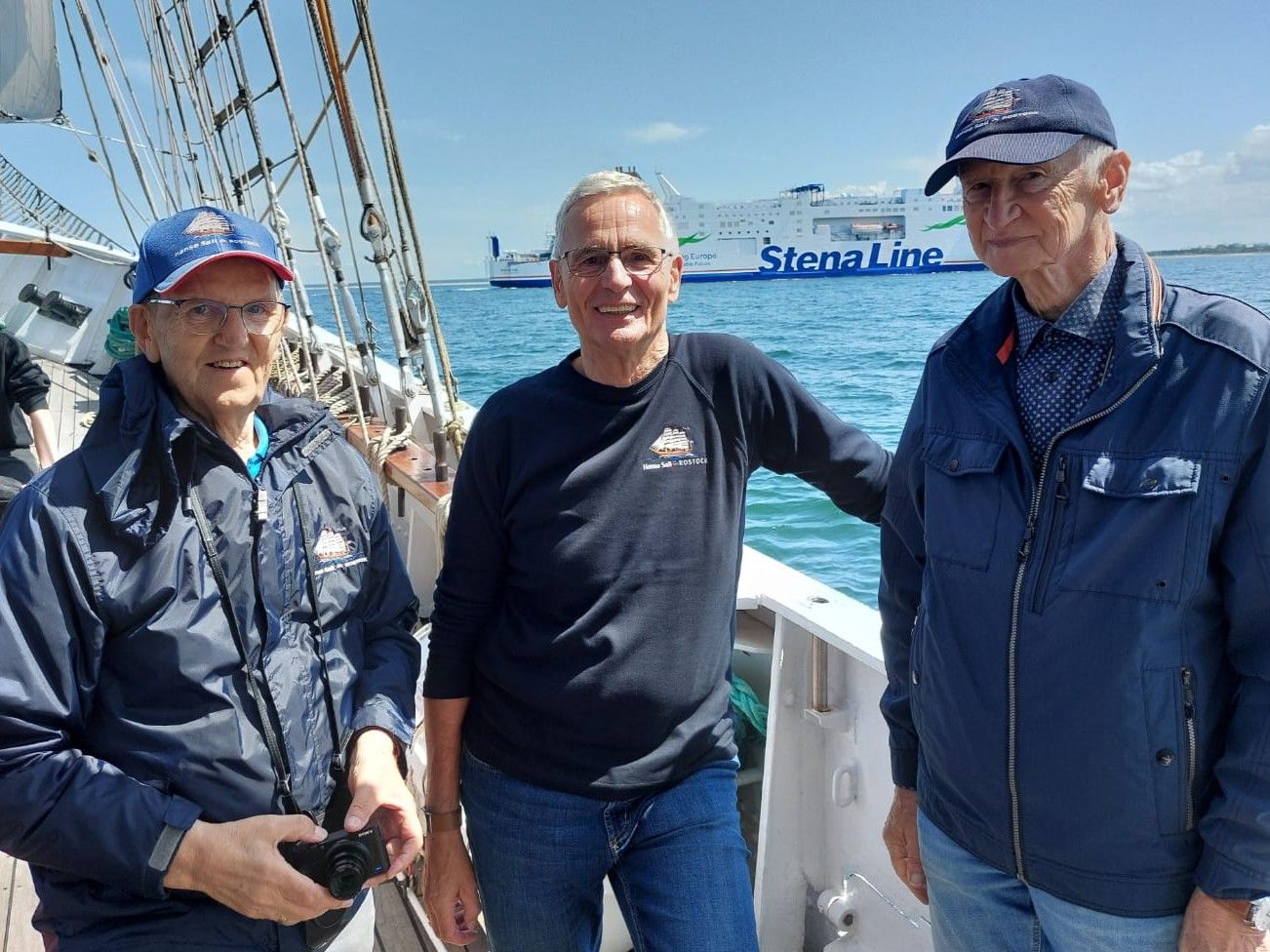 Drei Personen stehen auf einem Segelschiff