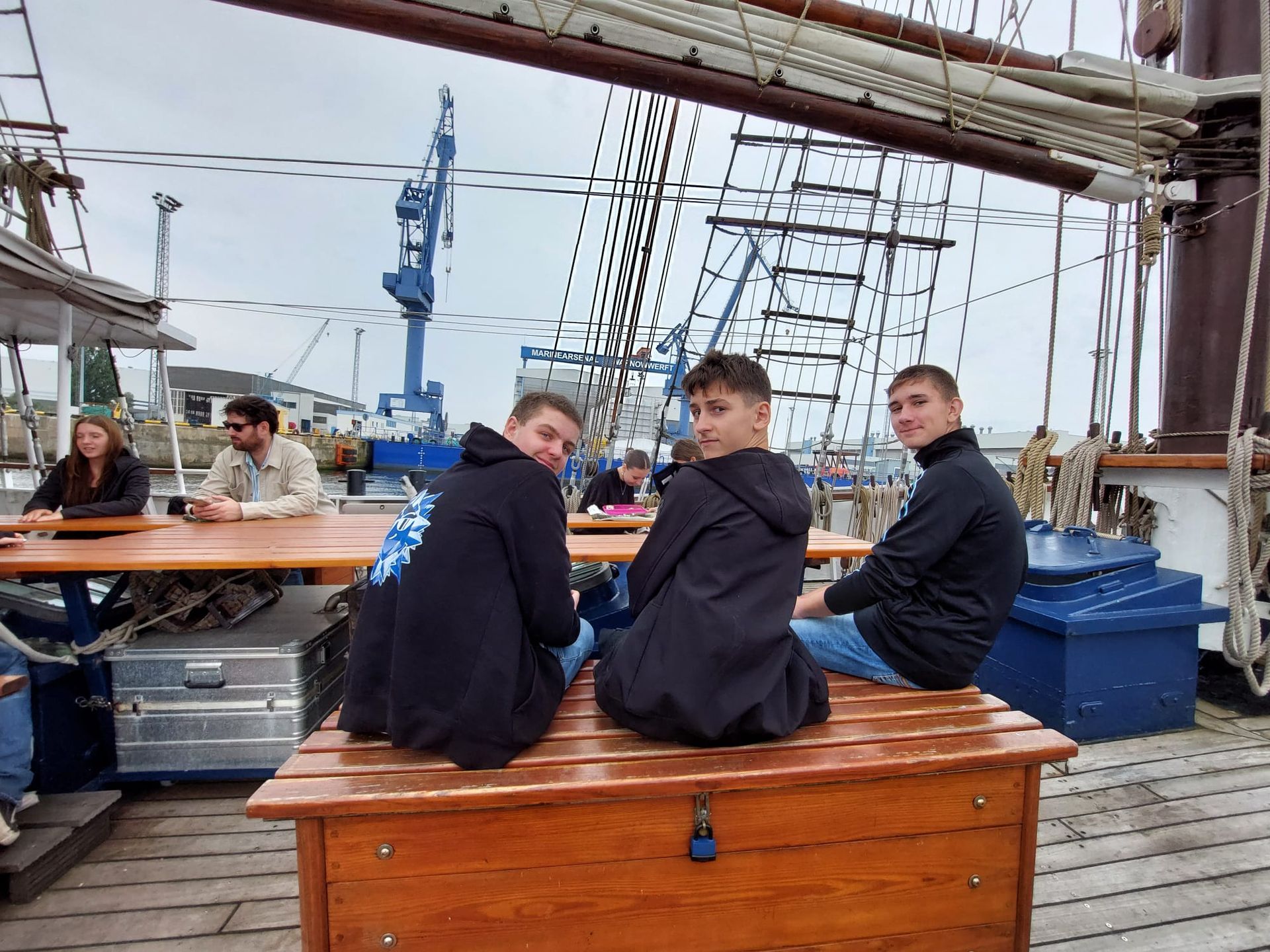 Drei Personen sitzen auf einem Segelschiff