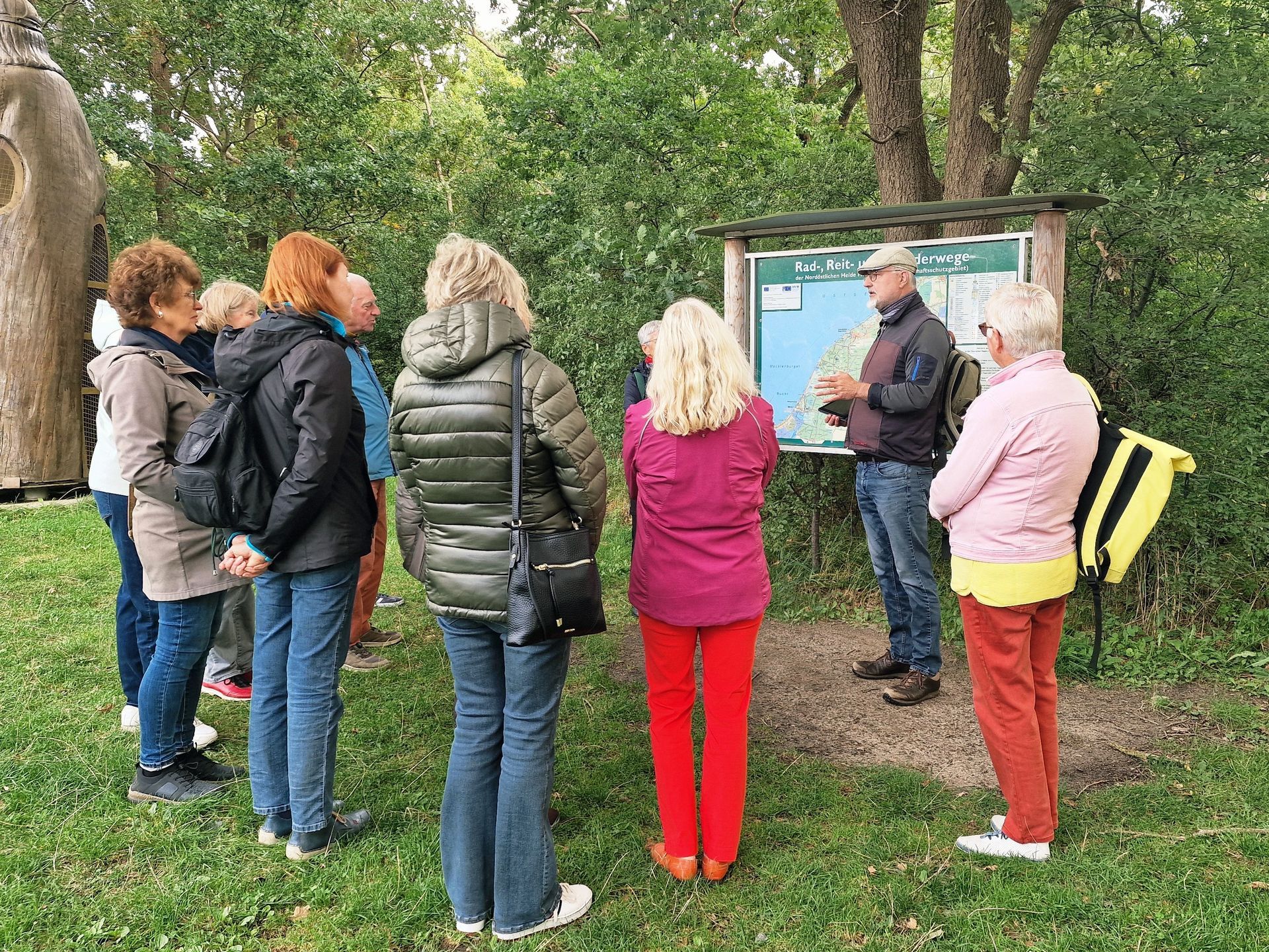 Eine Reisegruppe steht vor einem Hinweisschild