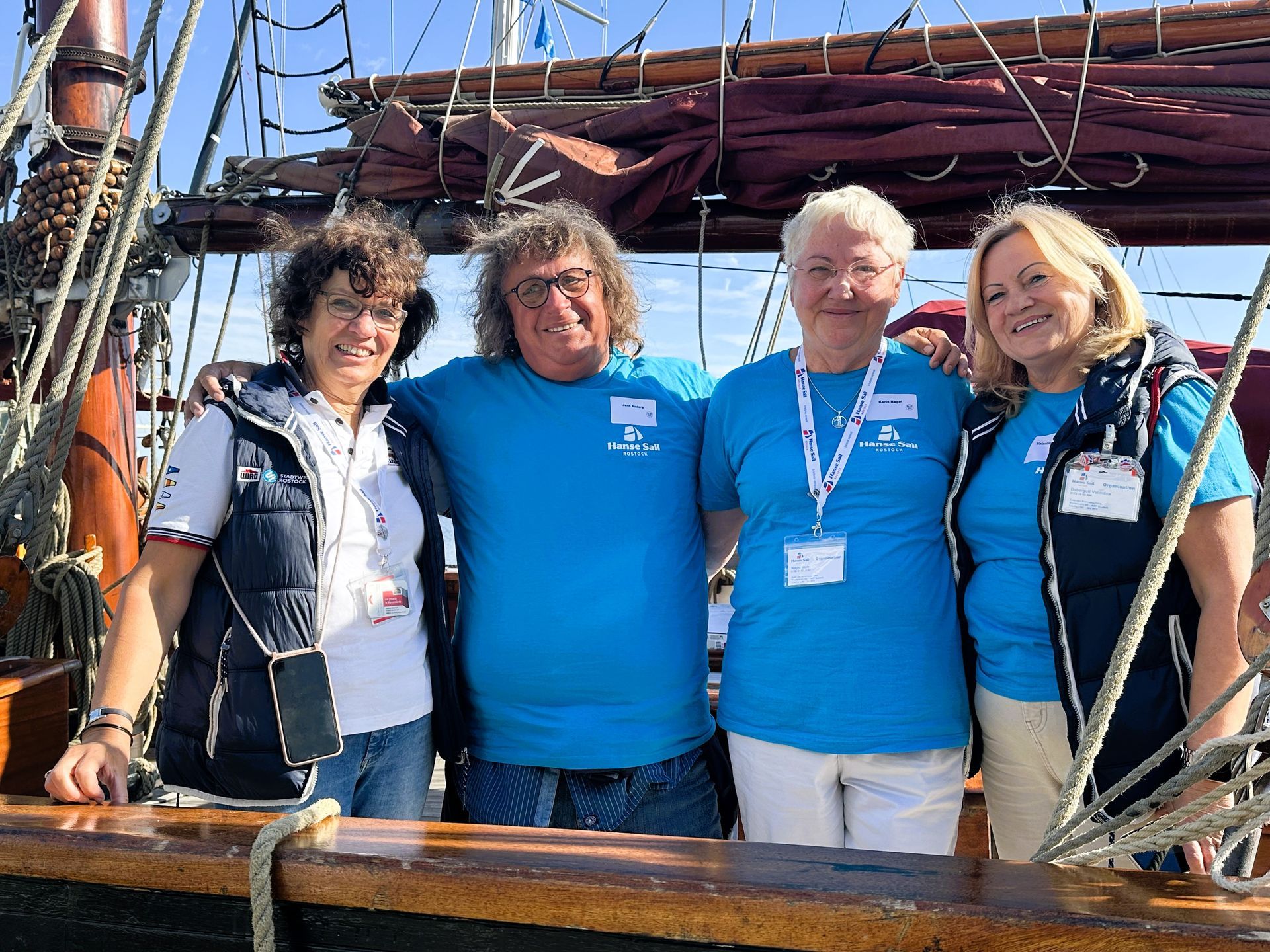 Eine Gruppe von vier Personen stehen auf dem Deck eines Segelboots.