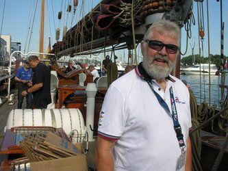 Ein Mann mit Bart und Sonnenbrille steht auf einem Boot.
