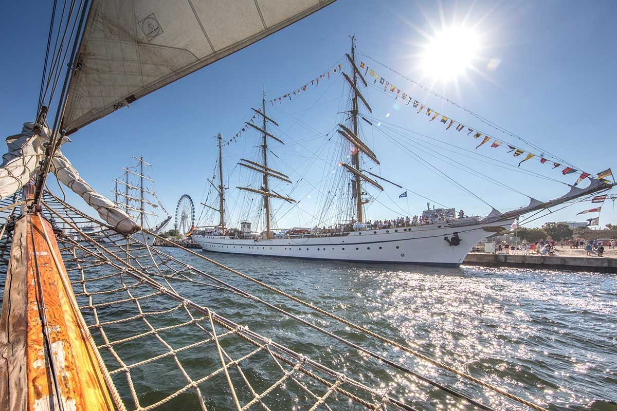 Ein Segelboot liegt in einem Hafen und die Sonne scheint durch die Segel.