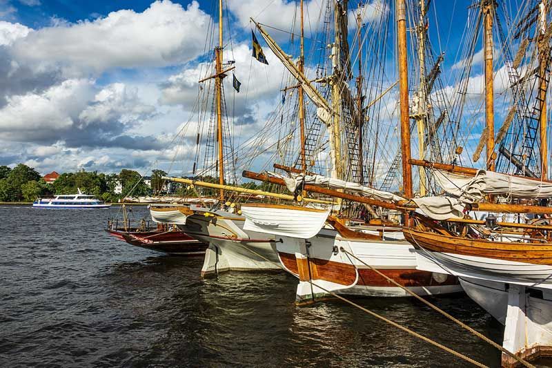 Eine Reihe Segelboote liegt in einem Hafen vor Anker.
